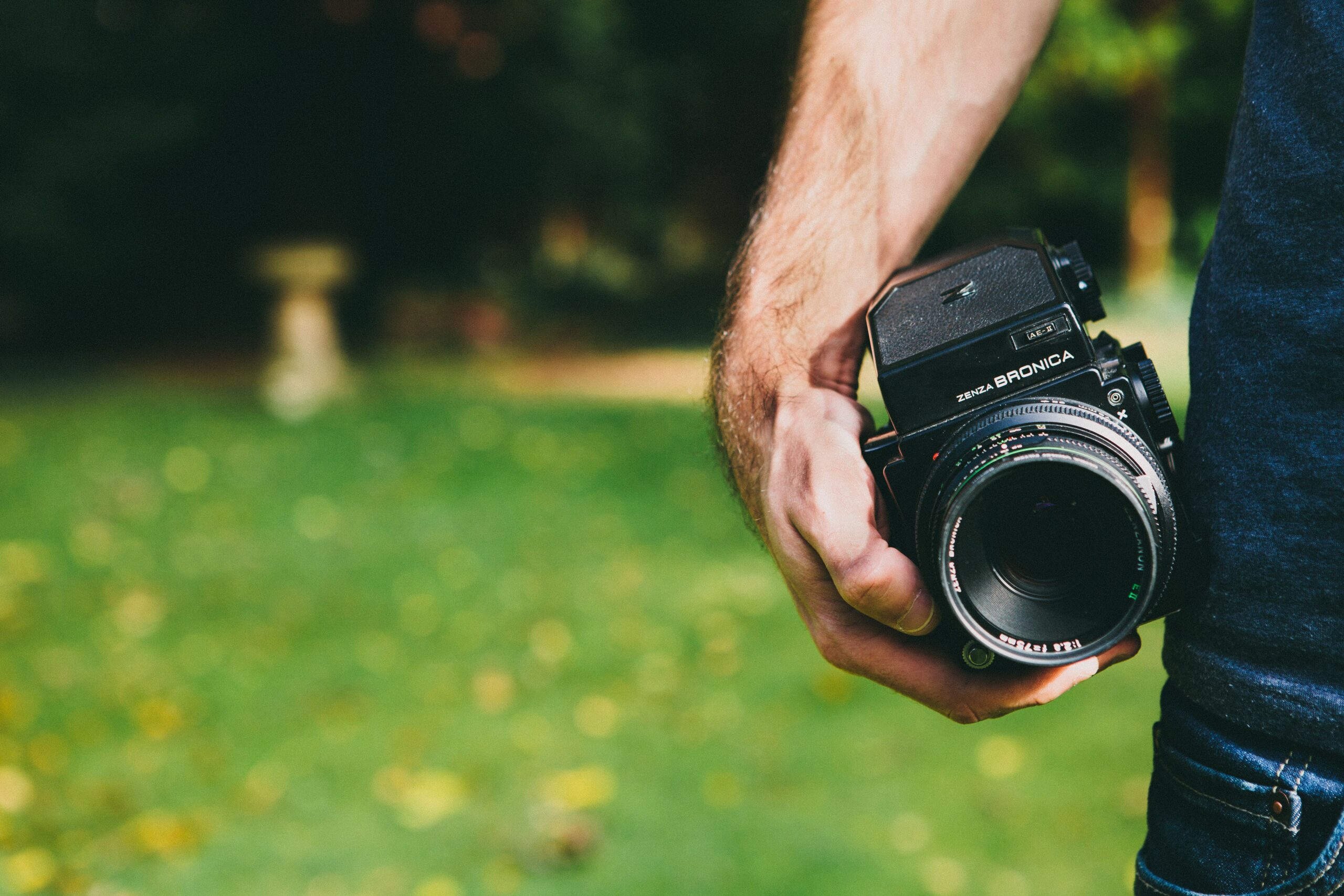 Close-up of a vintage medium format camera held outdoors, showing classic photography equipment.